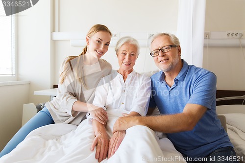 Image of happy family visiting senior woman at hospital