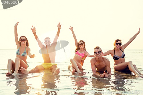 Image of smiling friends in sunglasses on summer beach