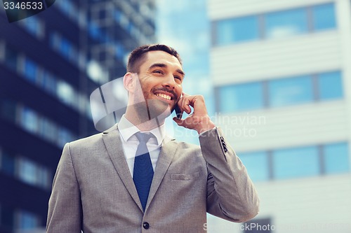 Image of smiling businessman with smartphone outdoors