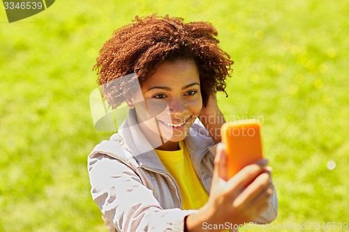 Image of happy african woman taking selfie with smartphone