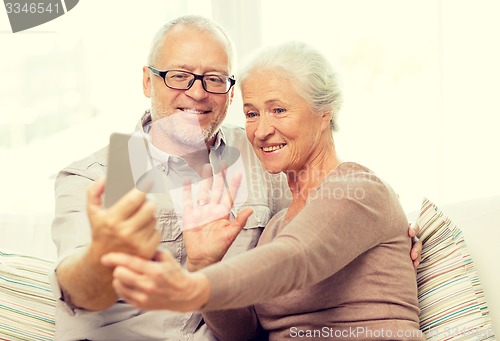 Image of happy senior couple with smartphone at home