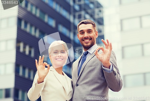 Image of smiling businessmen standing over office building