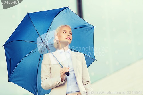 Image of young serious businesswoman with umbrella outdoors