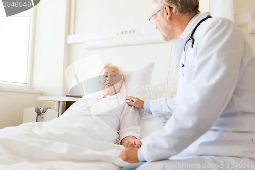 Image of doctor visiting senior woman at hospital ward