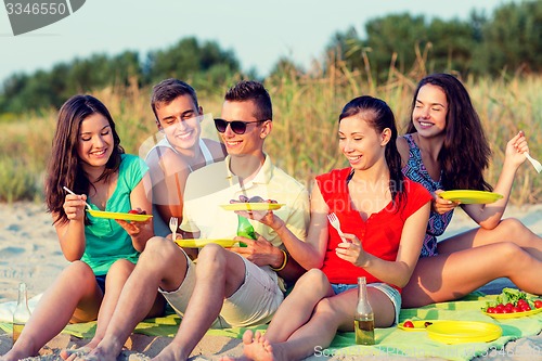 Image of smiling friends sitting on summer beach