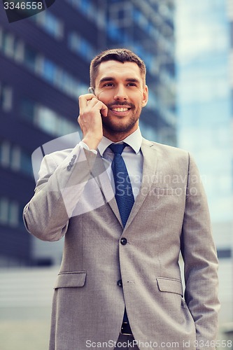 Image of smiling businessman with smartphone outdoors