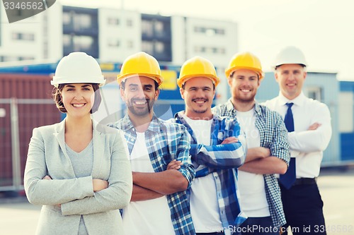 Image of group of smiling builders in hardhats outdoors