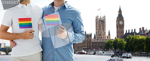 Image of close up of male gay couple with rainbow flags