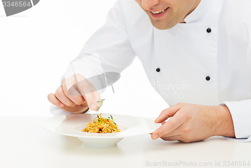 Image of close up of happy male chef cook decorating dish