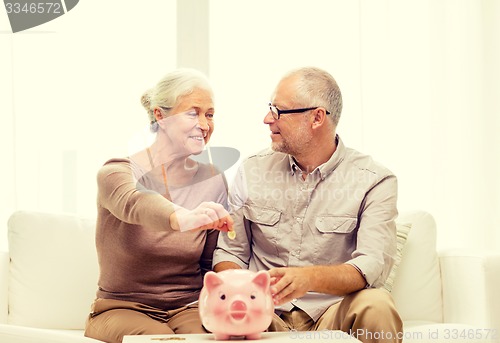 Image of senior couple with money and piggy bank at home