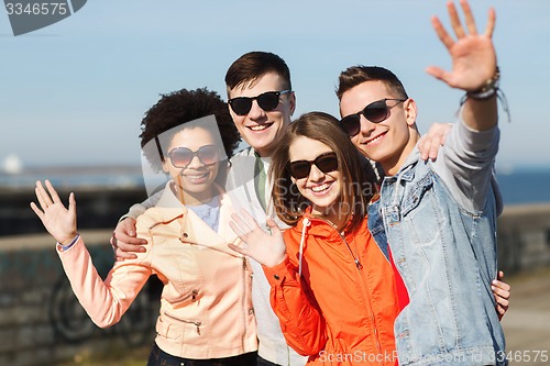 Image of happy teenage friends in shades waving hands