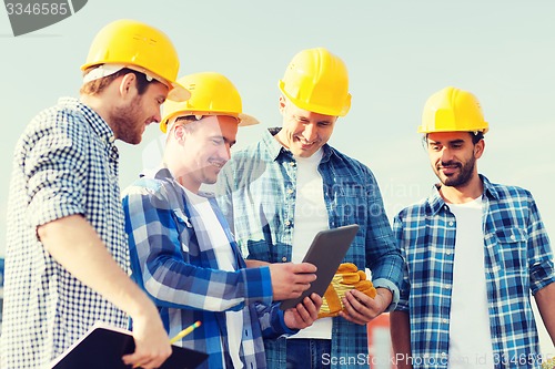 Image of group of smiling builders with tablet pc outdoors