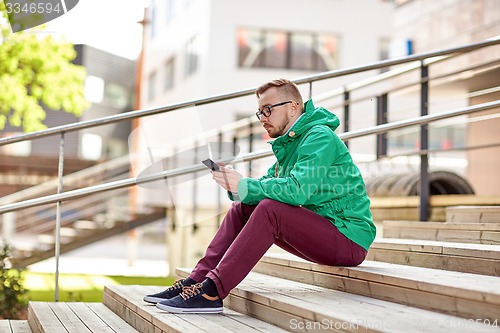 Image of young hipster man with smartphone in city