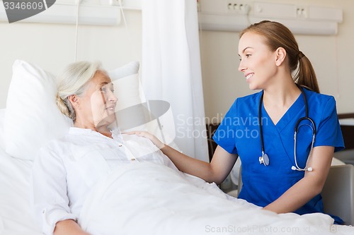 Image of doctor or nurse visiting senior woman at hospital