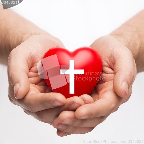 Image of male hands holding heart with cross symbol