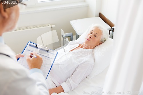 Image of senior woman and doctor with clipboard at hospital