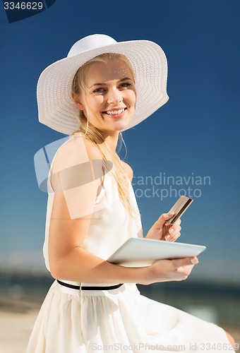 Image of woman in hat doing online shopping outdoors