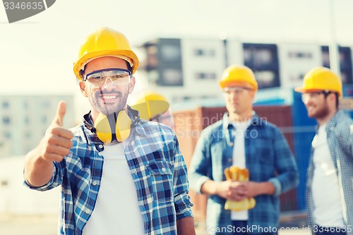 Image of group of smiling builders in hardhats outdoors