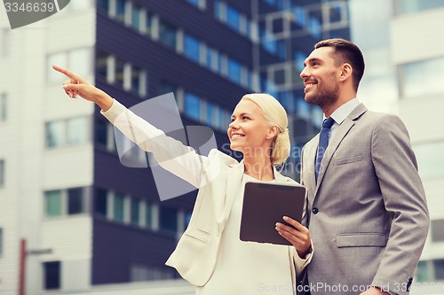 Image of smiling businessmen with tablet pc outdoors