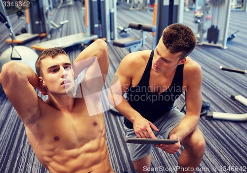 Image of men flexing abdominal muscles in gym