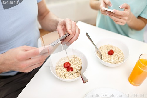 Image of close up of couple with smartphones at breakfast