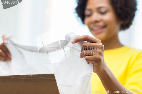 Image of happy african young woman with parcel box at home