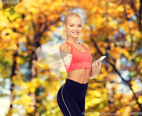 Image of smiling sporty woman with smartphone