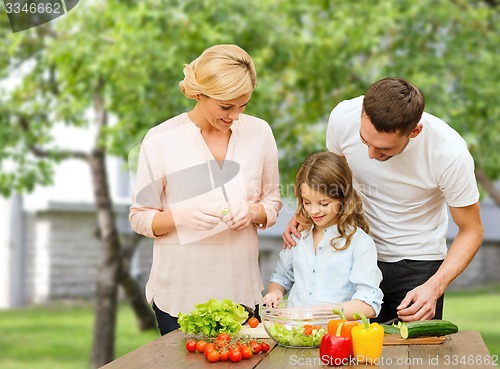 Image of happy family cooking vegetable salad for dinner