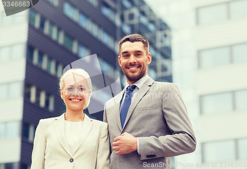 Image of smiling businessmen standing over office building