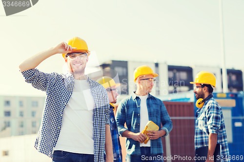 Image of group of smiling builders in hardhats outdoors