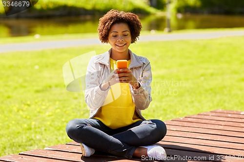 Image of happy african young woman messaging on smartphone