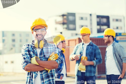 Image of group of smiling builders in hardhats outdoors