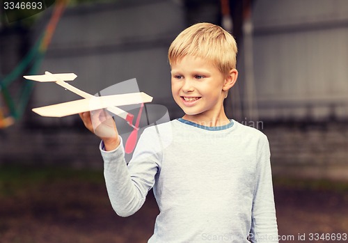 Image of smiling little boy holding a wooden airplane model