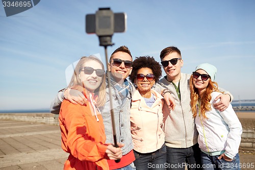 Image of smiling friends taking selfie with smartphone