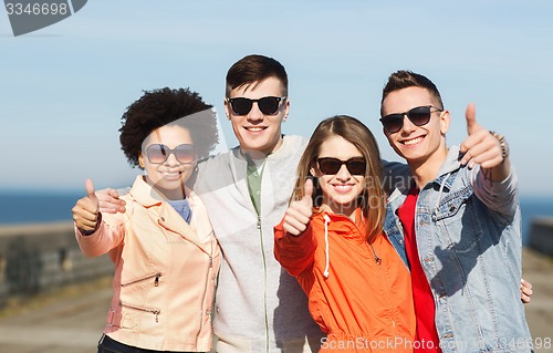 Image of happy teenage friends in shades hugging outdoors
