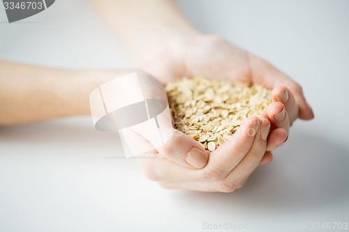 Image of close up of woman hands holding oatmeal flakes