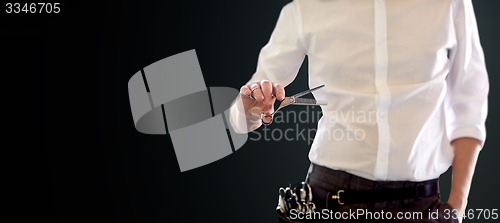 Image of close up of male stylist with scissors over black