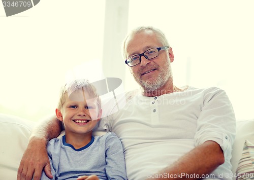 Image of smiling grandfather and grandson at home