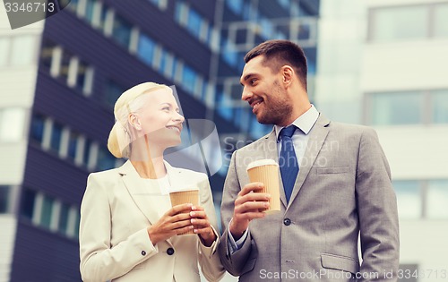 Image of smiling businessmen with paper cups outdoors