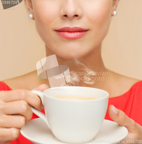 Image of smiling woman in red dress with cup of coffee