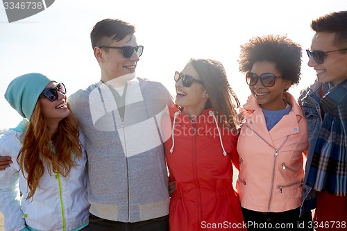 Image of happy teenage friends in shades talking on street