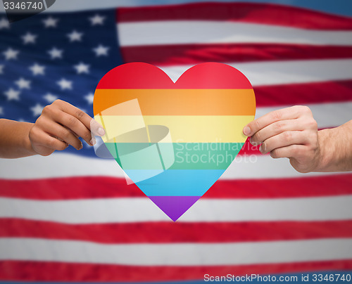 Image of hands with rainbow heart shape over american flag