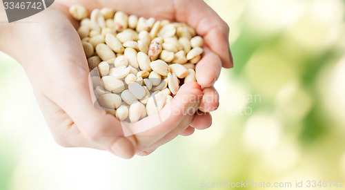 Image of close up of woman hands holding peeled peanuts