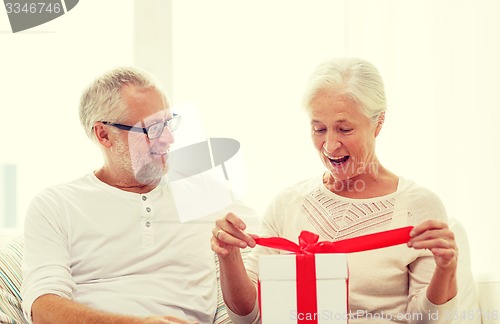 Image of happy senior couple with gift box at home