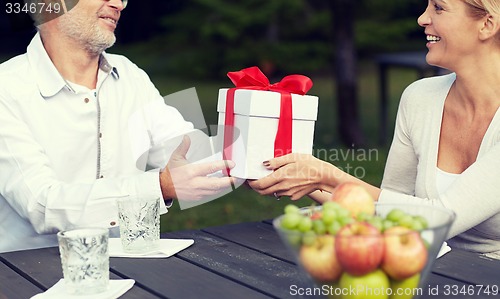 Image of happy family giving present in summer garden