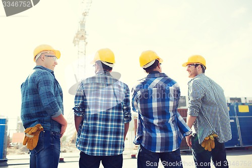 Image of group of smiling builders in hardhats outdoors