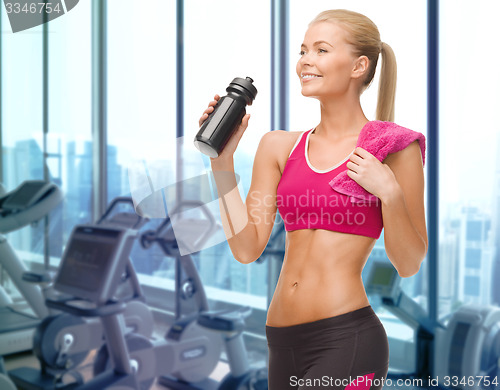 Image of happy woman drinking water from bottle in gym