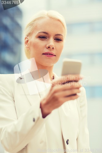 Image of serious businesswoman with smartphone outdoors