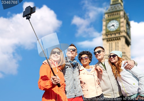 Image of smiling friends taking selfie with smartphone