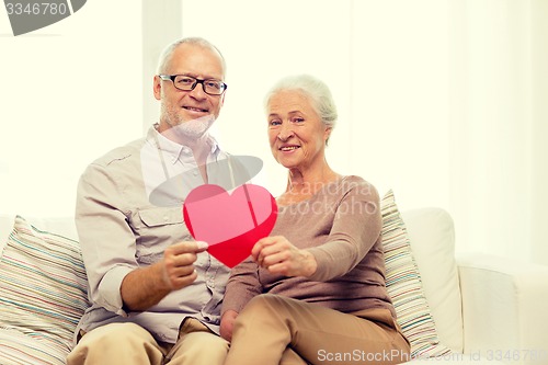 Image of happy senior couple with red heart shape at home
